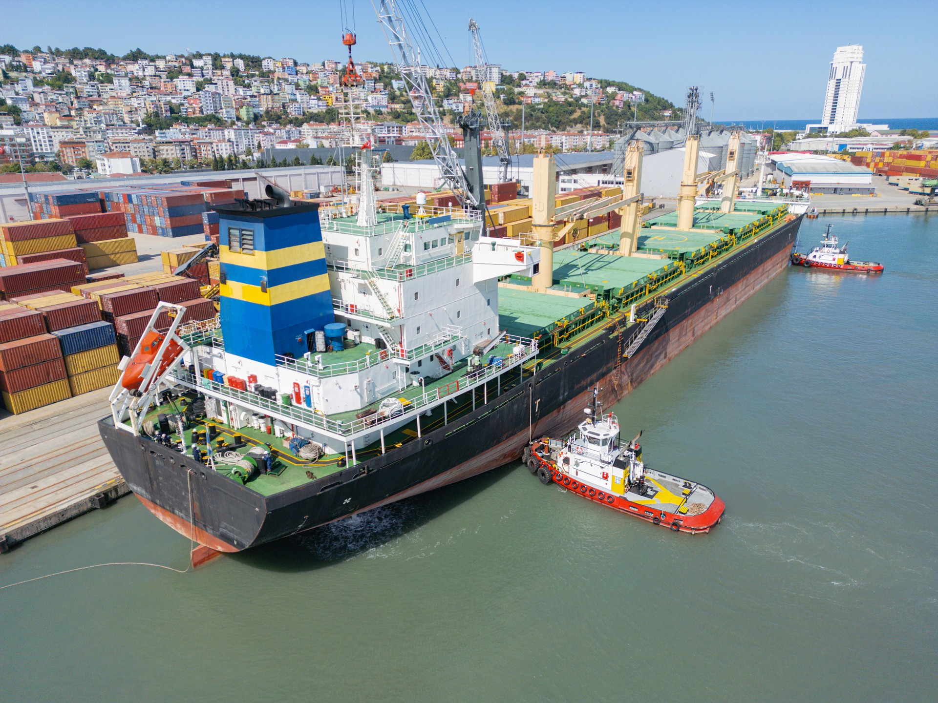 Tugboat accompany the cargo ship as it enters the port. International ocean transport.